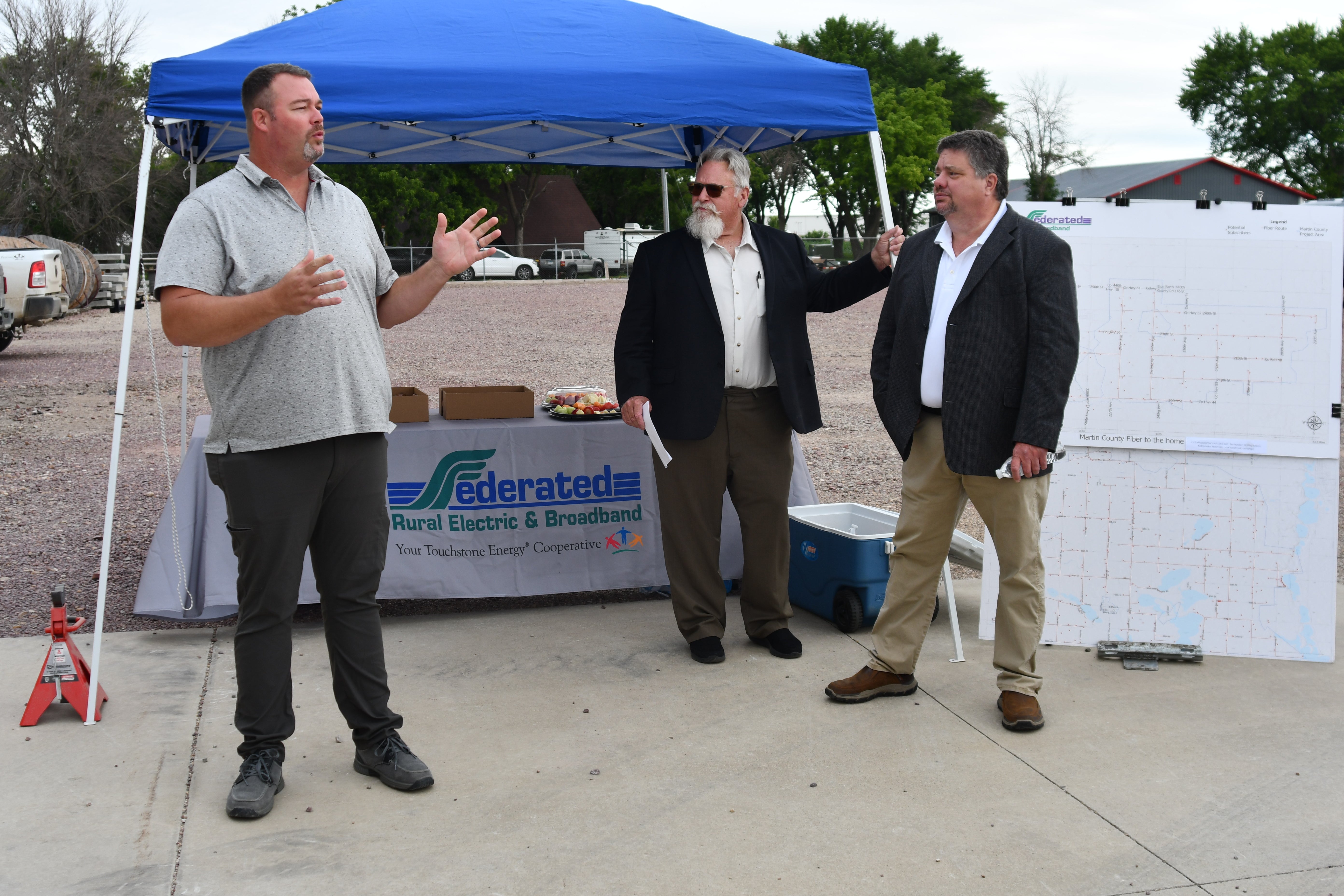 Speaker Steve Blaufuss addressing crowd at Martin County groundbreaking ceremony. FREA General Manger, Scott Reimer, and Broadband Operations Manager, Troy Rasmussen, look on.